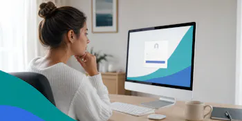 Woman sitting at a desk looking thoughtfully at a computer screen displaying a